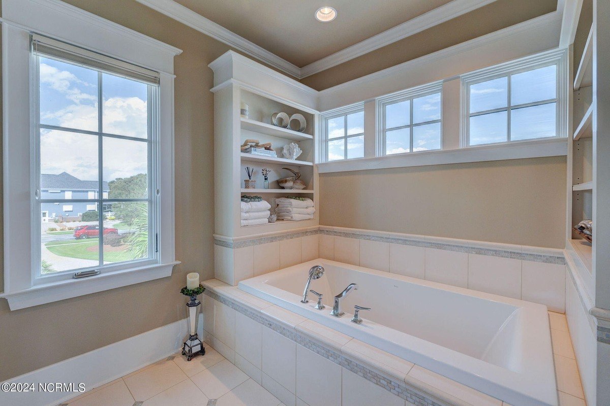 Bathroom has built-in shelves, soaking tub, and tiled walls.