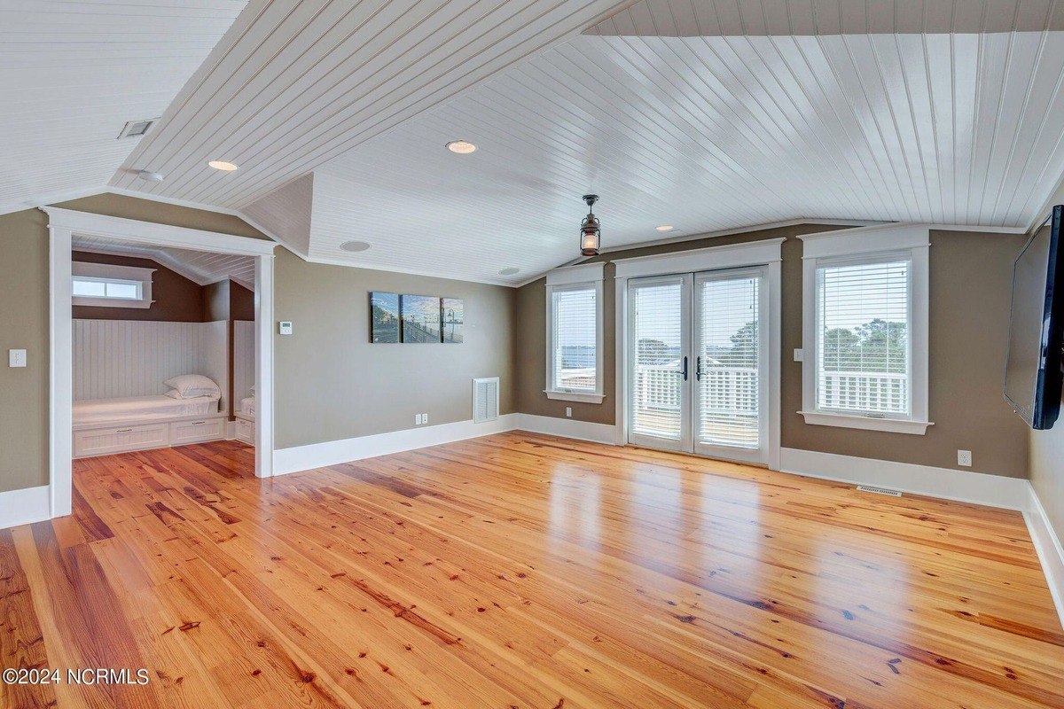 Room has hardwood floors, vaulted ceiling, and French doors.