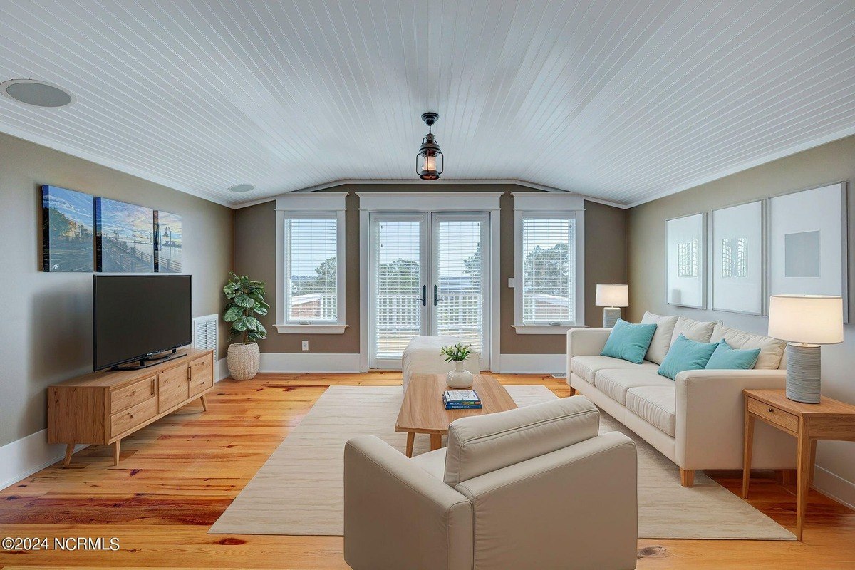 Living area has hardwood floors, vaulted ceiling, and seating area.