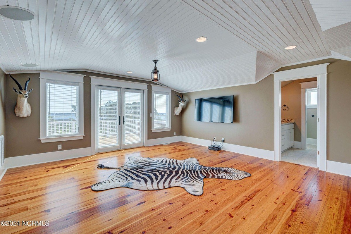 Room has hardwood floors, vaulted ceiling, and zebra rug.