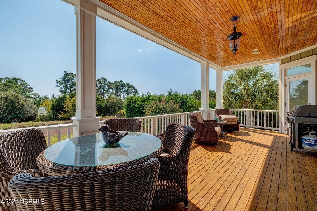 Porch has wicker furniture, glass-top table, and wood flooring.