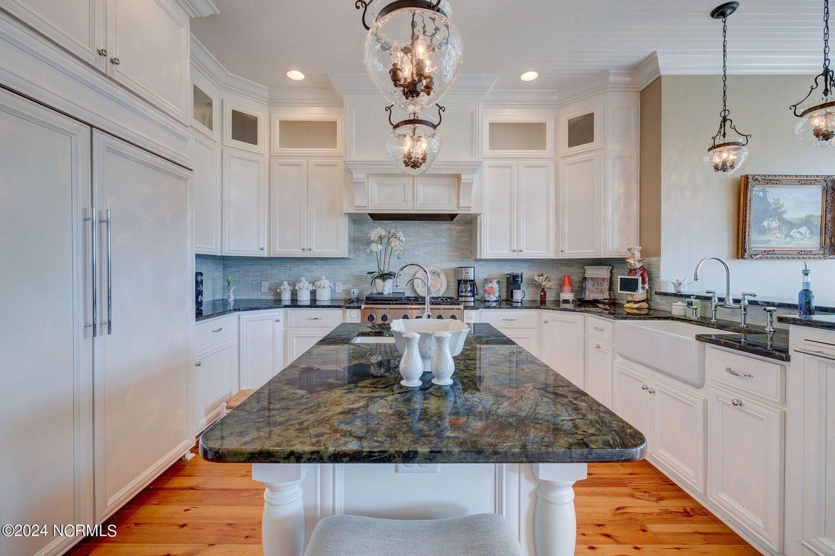 Kitchen has white cabinets, granite countertops, and island.