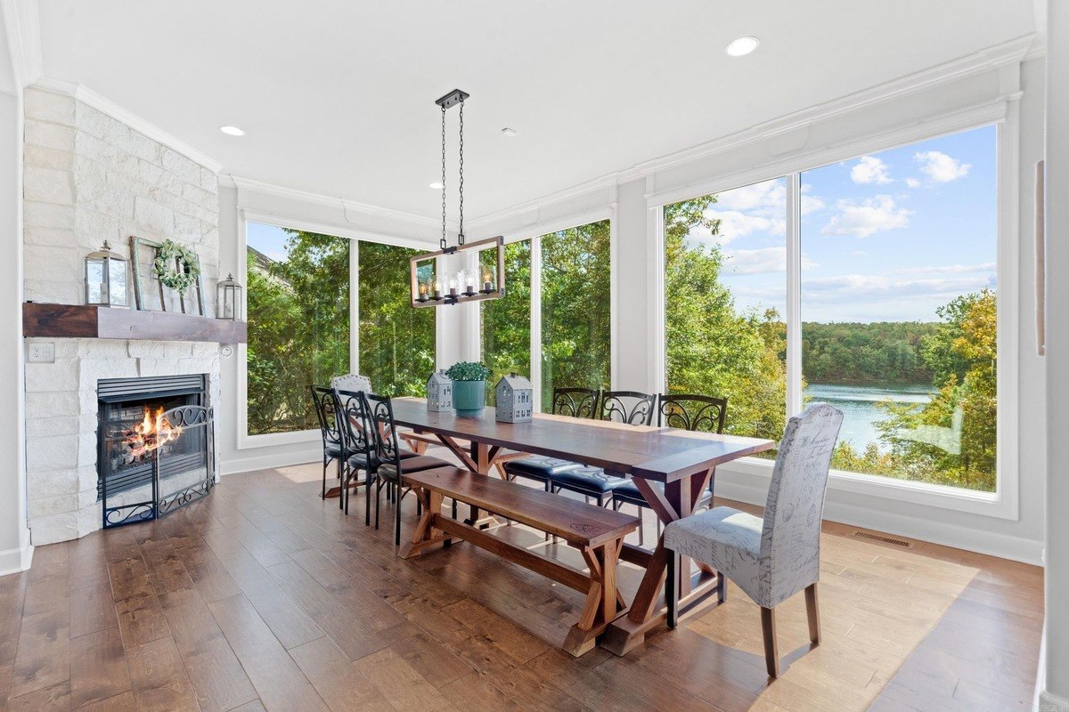 Dining room with a long wooden table, bench seating, and large windows overlooking a lake.