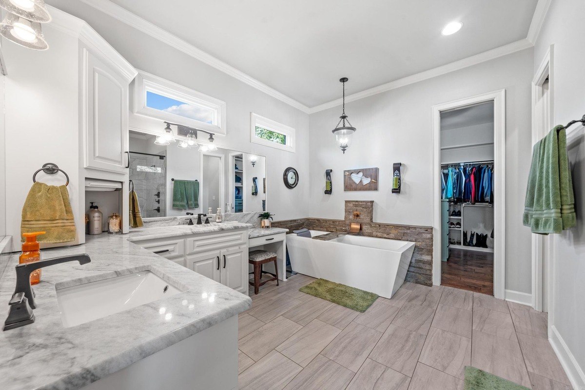 Master bathroom with double vanities, a freestanding bathtub, and a walk-in closet.