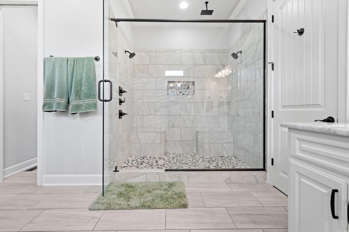 Large walk-in shower with glass enclosure and stone tile floor.