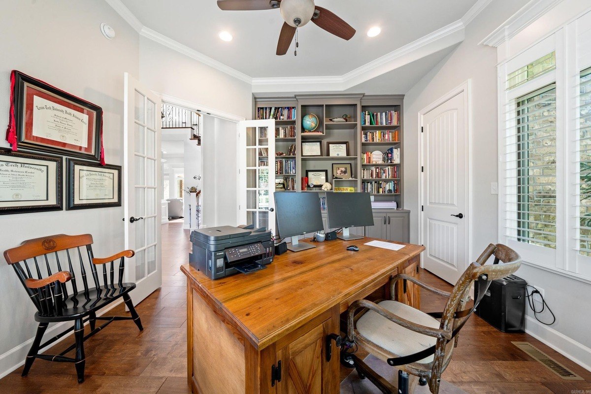 Home office with a wooden desk, two computer monitors, and built-in bookshelves.