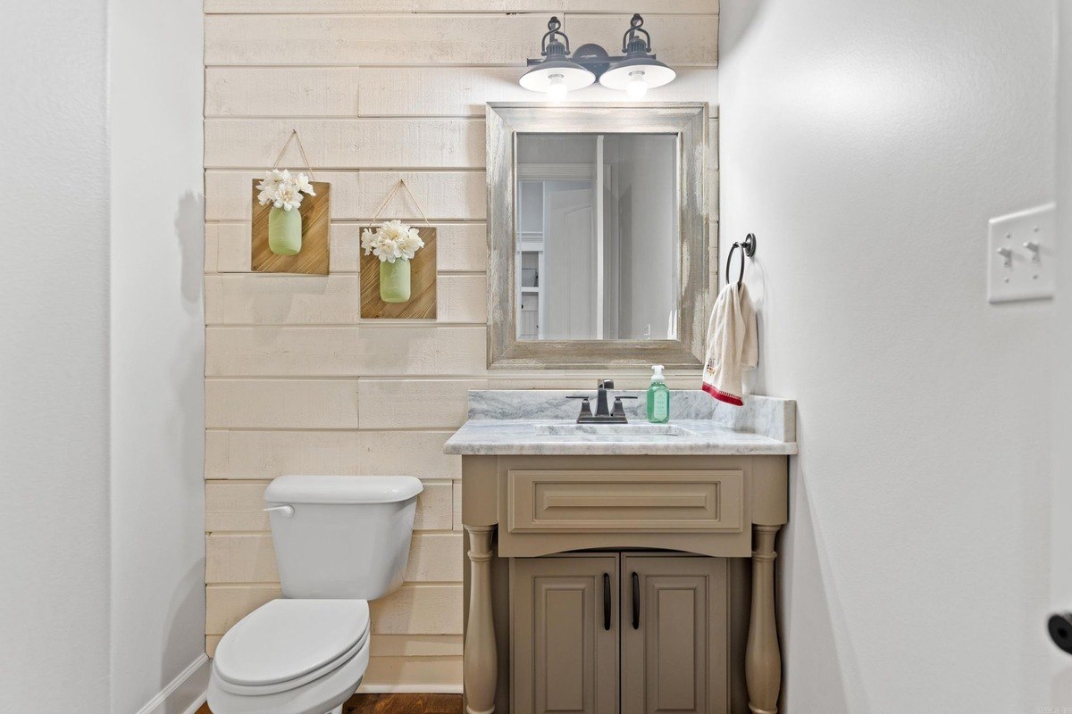 Powder room with a pedestal sink, toilet, and shiplap walls.