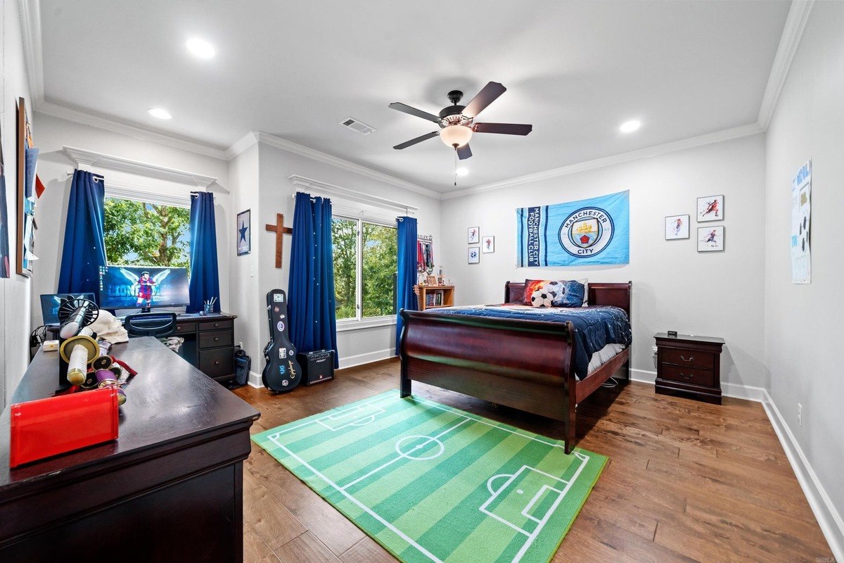 Bedroom with a dark wood sleigh bed, a desk, and a soccer field rug.