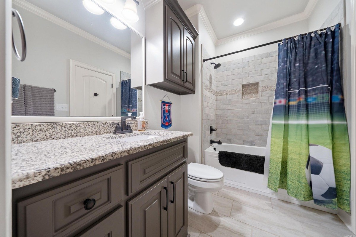 Bathroom with dark gray cabinets, granite countertops, and a shower/tub combo.