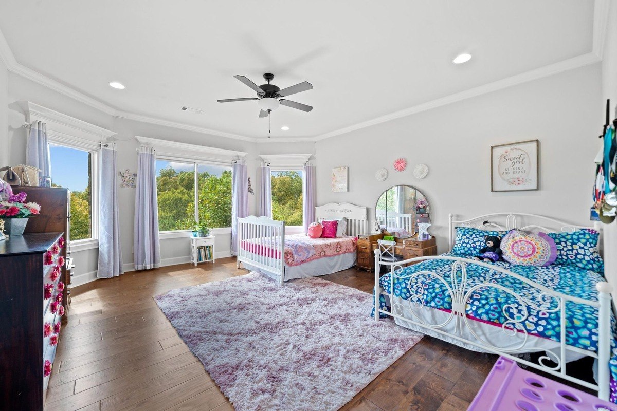 Shared bedroom with two beds, a dresser, and large windows offering a view of trees.