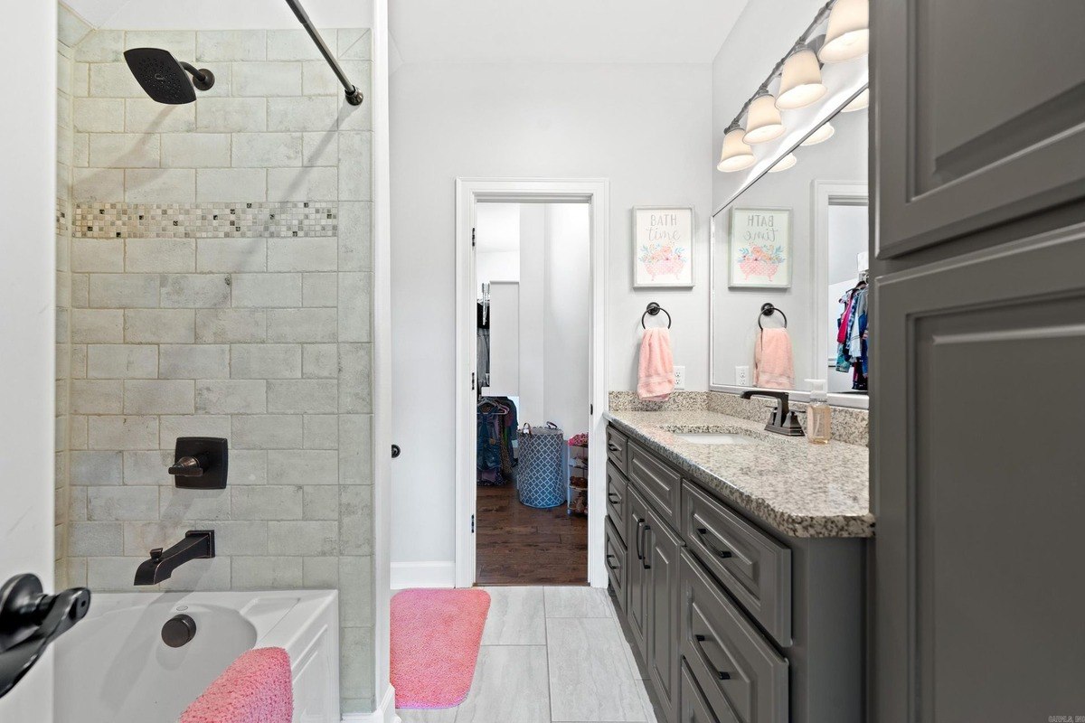 Bathroom with gray cabinets, granite countertops, and a shower/tub combination.