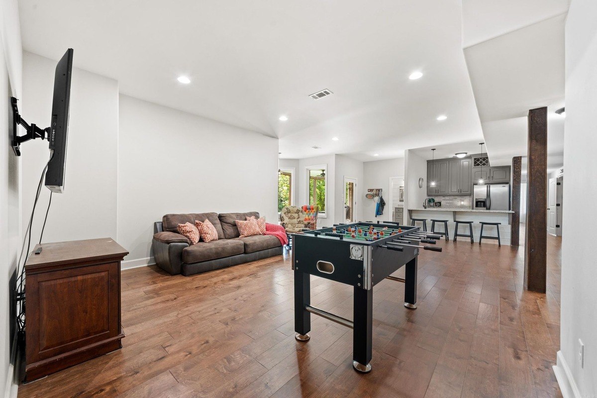 Game room with foosball table, couch, and hardwood floors.