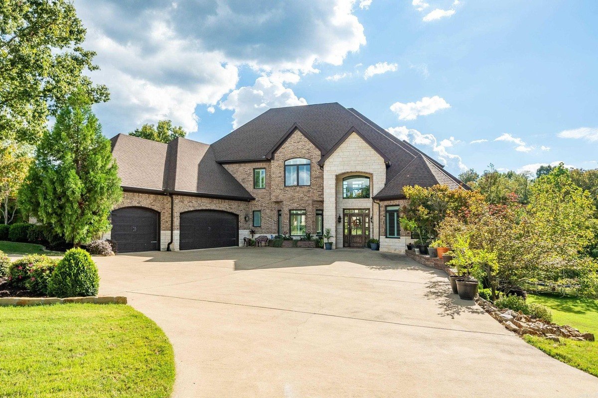 Large brick house with a three-car garage and landscaping sits on a large lot.