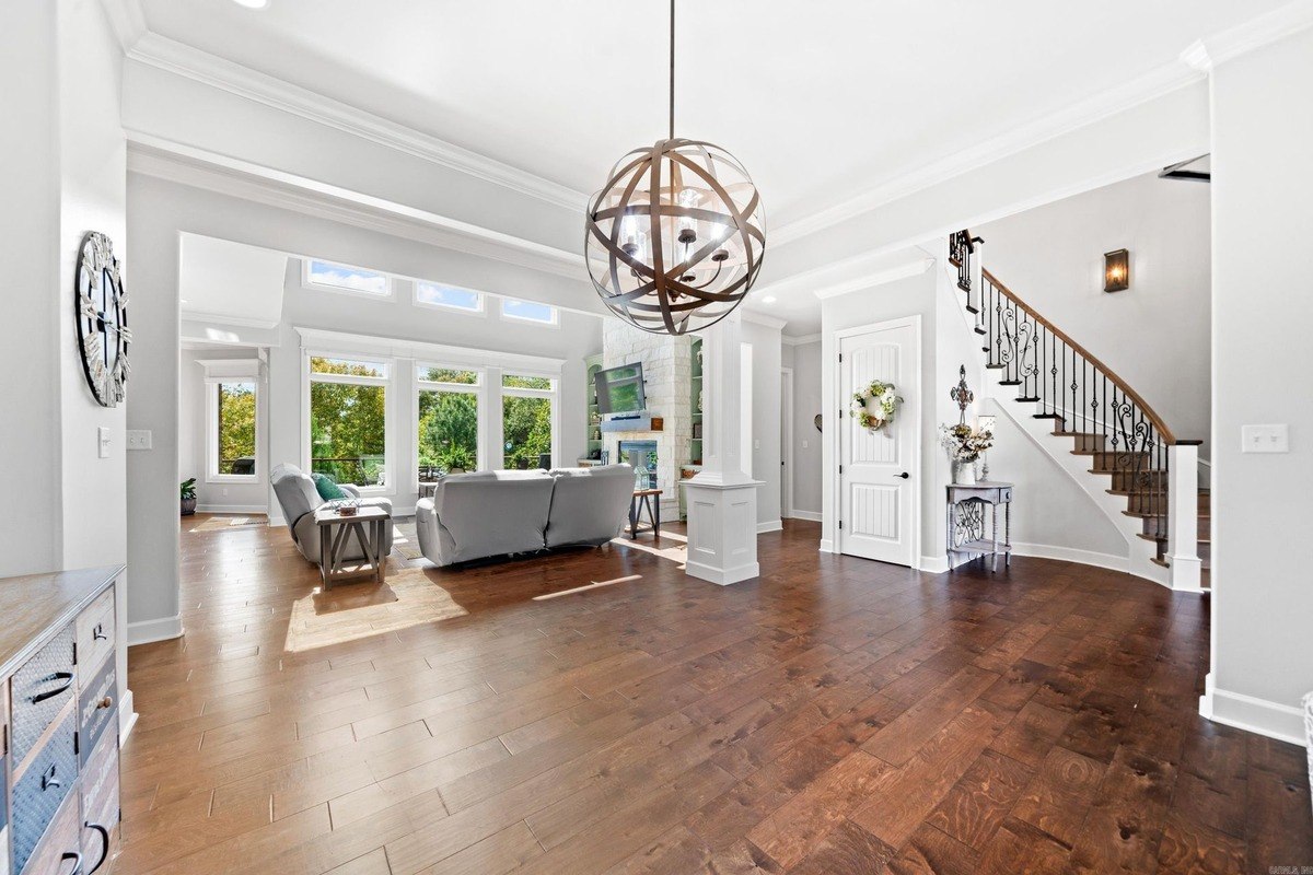 Open floor plan with hardwood floors, large windows, and a curved staircase.