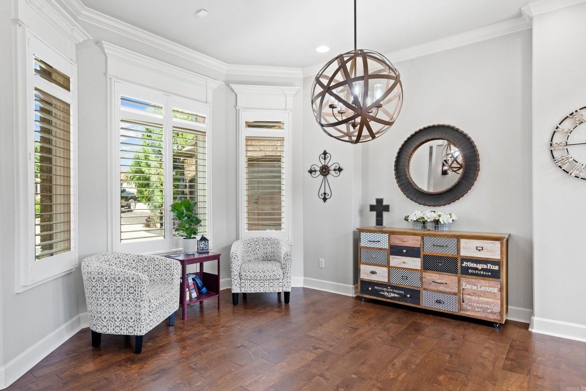 Living room with hardwood floors, two armchairs, and a decorative dresser.