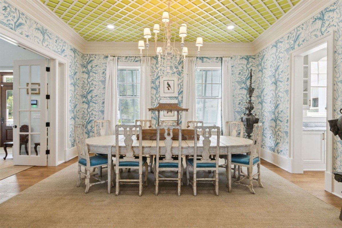 Formal dining room has a large table with chairs, patterned wallpaper, and a unique ceiling.