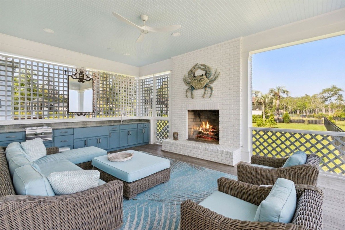 Outdoor living space has wicker furniture, a fireplace, and a view of a grassy area.