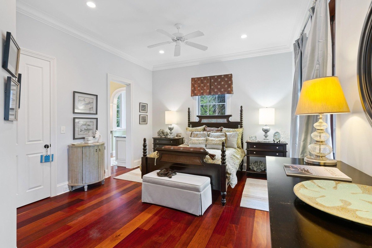 Bedroom features hardwood floors, a dark wood bed, and a ceiling fan.