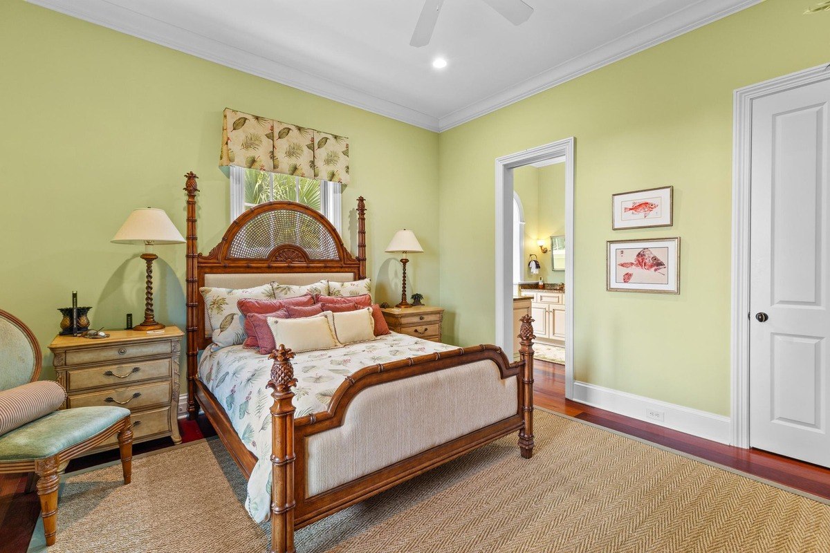 Bedroom with light green walls features a wood bed, nightstands, and a ceiling fan.