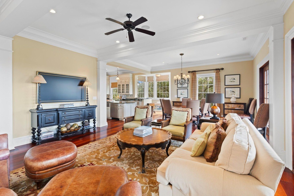 Living room features hardwood floors, a large sofa, armchairs, coffee table, and a ceiling fan.