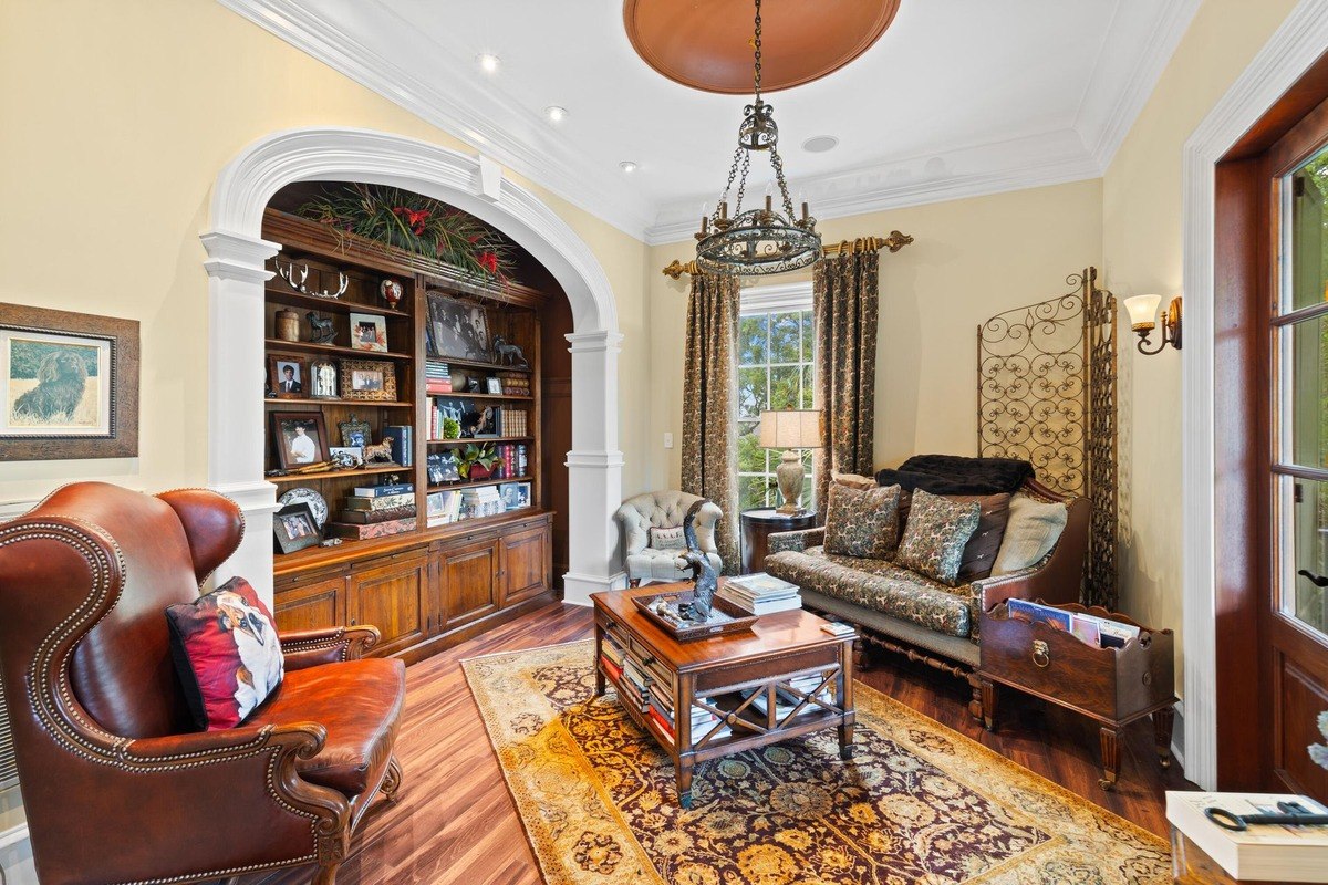 Living room features hardwood floors, a leather armchair, a sofa, and built-in bookshelves.