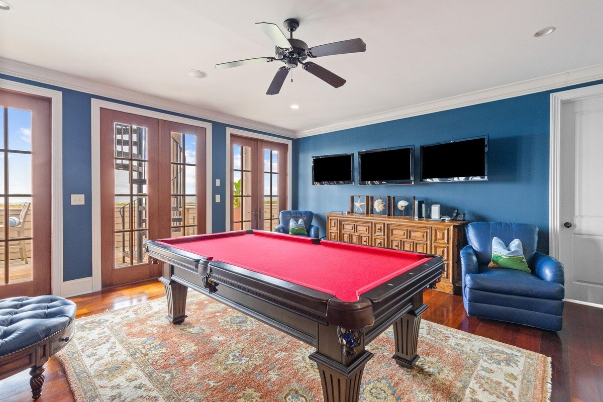 Game room features a pool table, flat-screen TVs, and a ceiling fan.