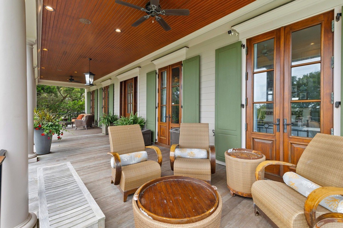 Porch has wicker chairs, a wooden coffee table, and a wood-paneled ceiling.