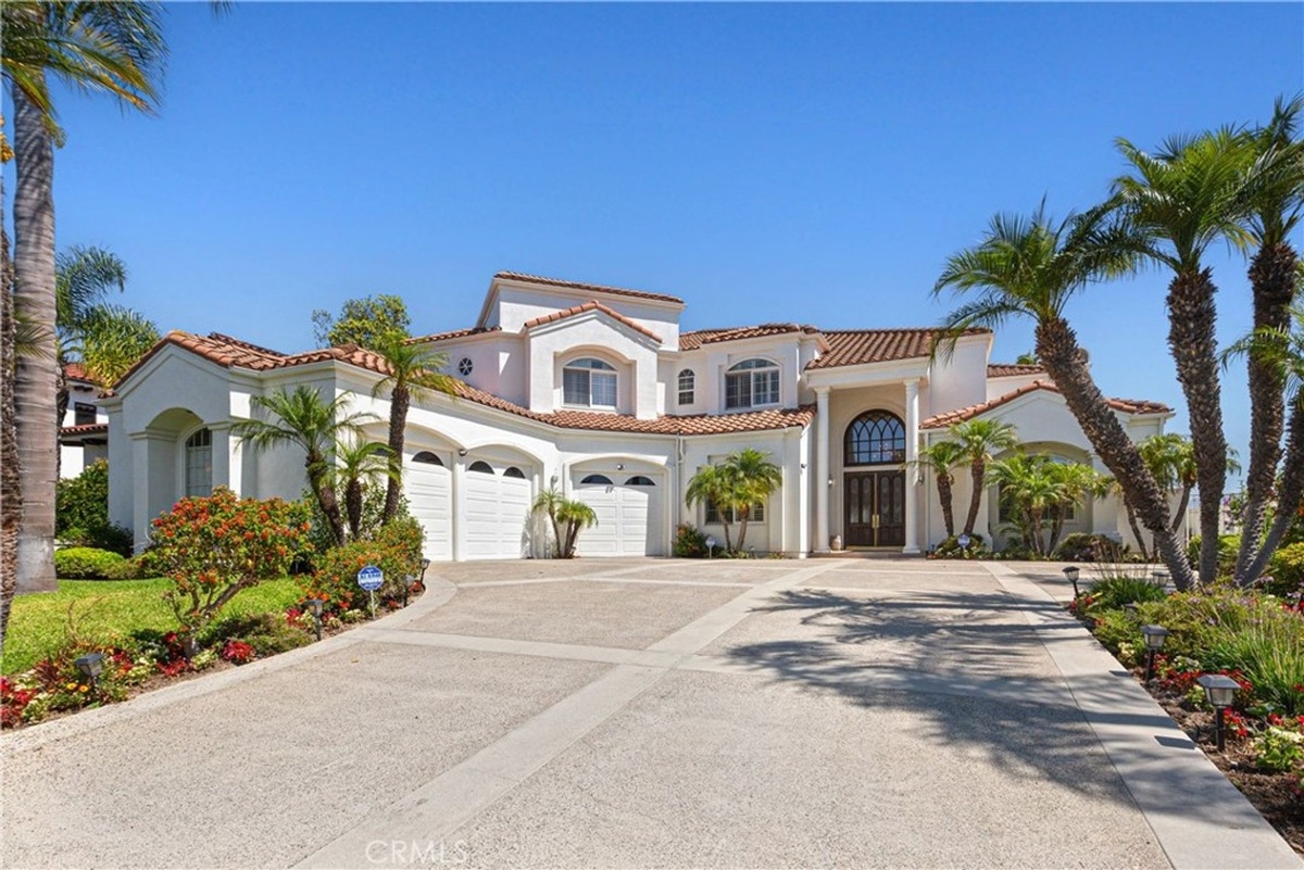 Mediterranean-style exterior with white stucco walls, red-tile roof, and lush landscaping.