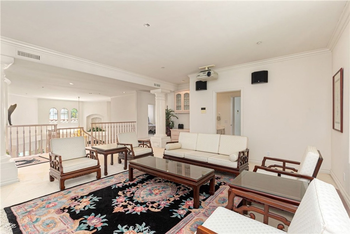 Upstairs seating area with white furniture, floral accents, and a projector setup for movies.