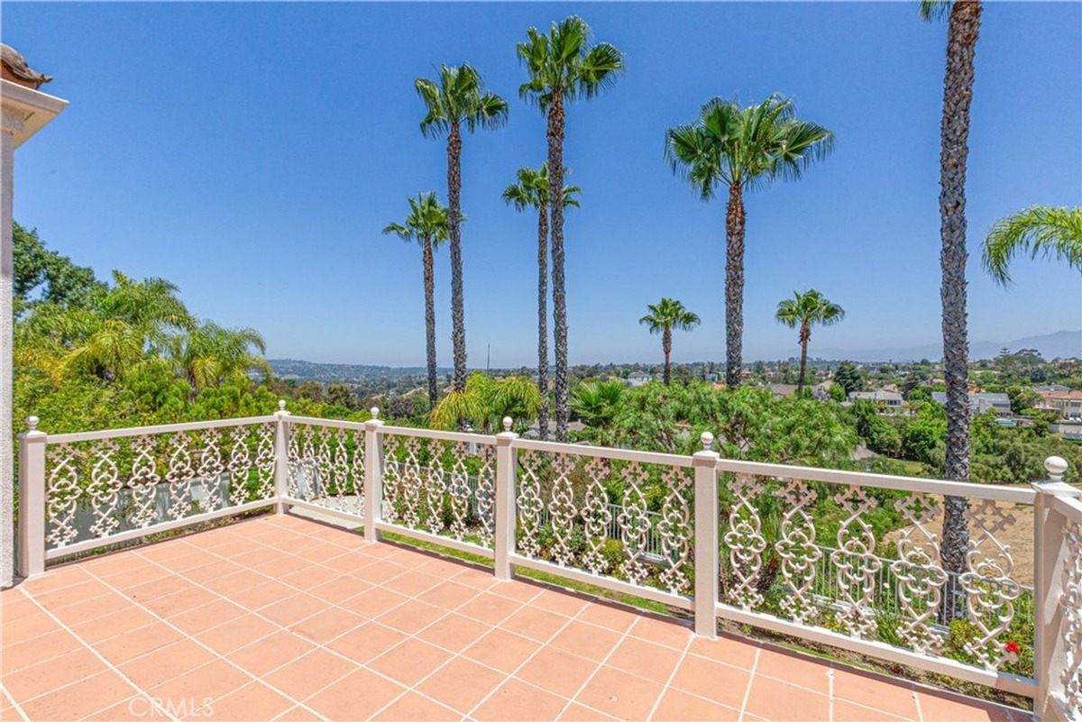 Balcony offers a scenic view of palm trees and a distant cityscape.