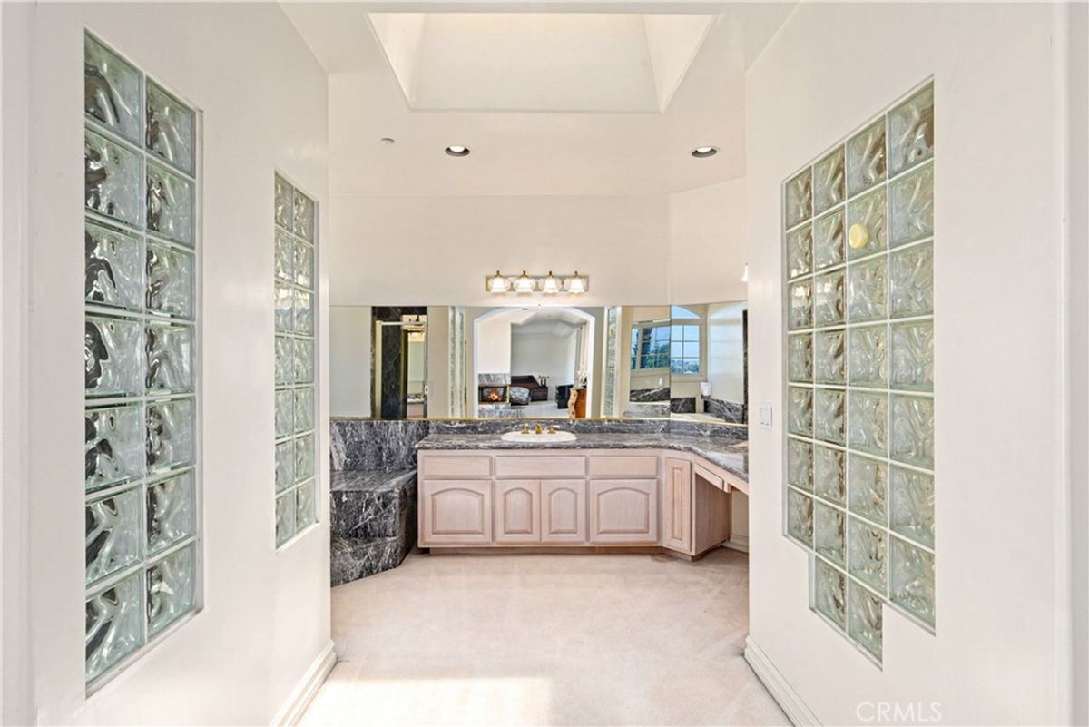 Marble-accented bathroom showcases dual sinks and glass block accents.