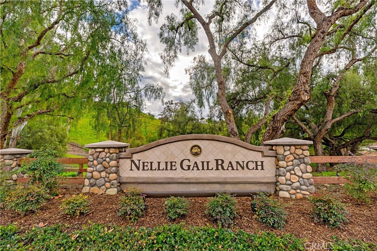 Entrance sign displaying "Nellie Gail Ranch" surrounded by stone accents and lush greenery.