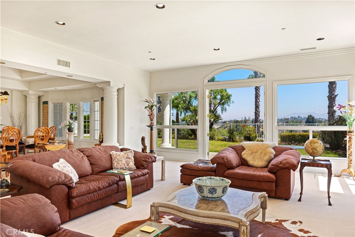 Sitting area adjacent to a dining space showcasing ornate furniture and large windows.