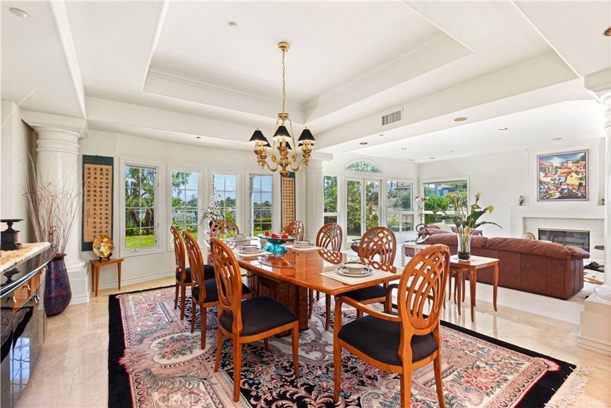 Formal dining room with a polished wood table, chandelier, and views of the landscaped garden.