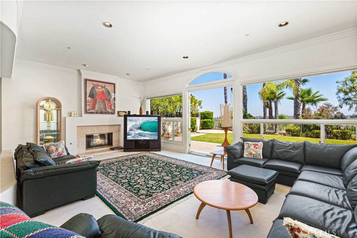 Family room with black leather sectional seating, a large TV, and access to an outdoor patio.