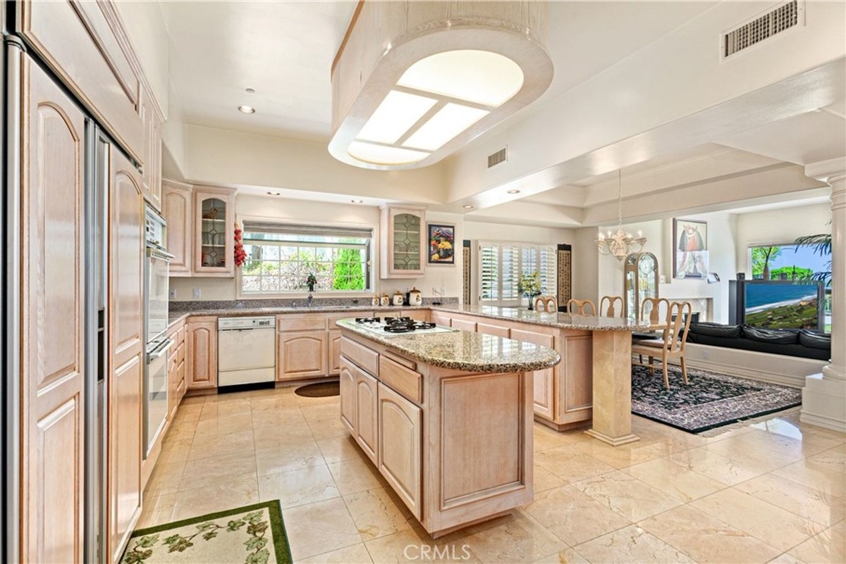 Spacious kitchen with granite countertops, light wood cabinets, and a central island.