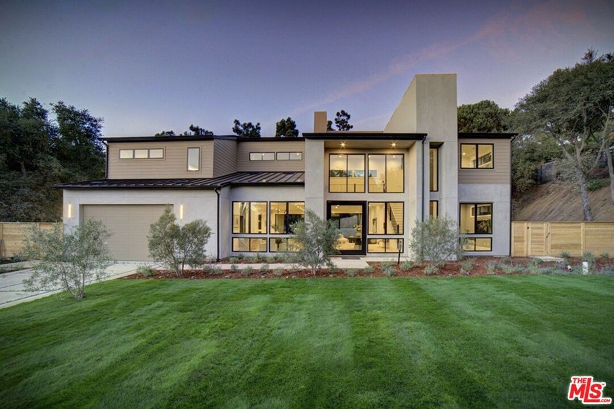 Modern facade with large windows and a sleek exterior design surrounded by manicured greenery.