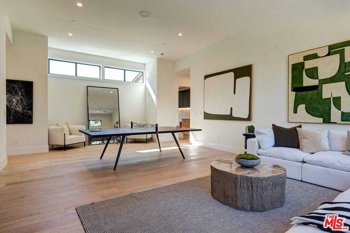 Recreation room with a ping pong table, minimal seating, and large abstract artwork decorating the walls.