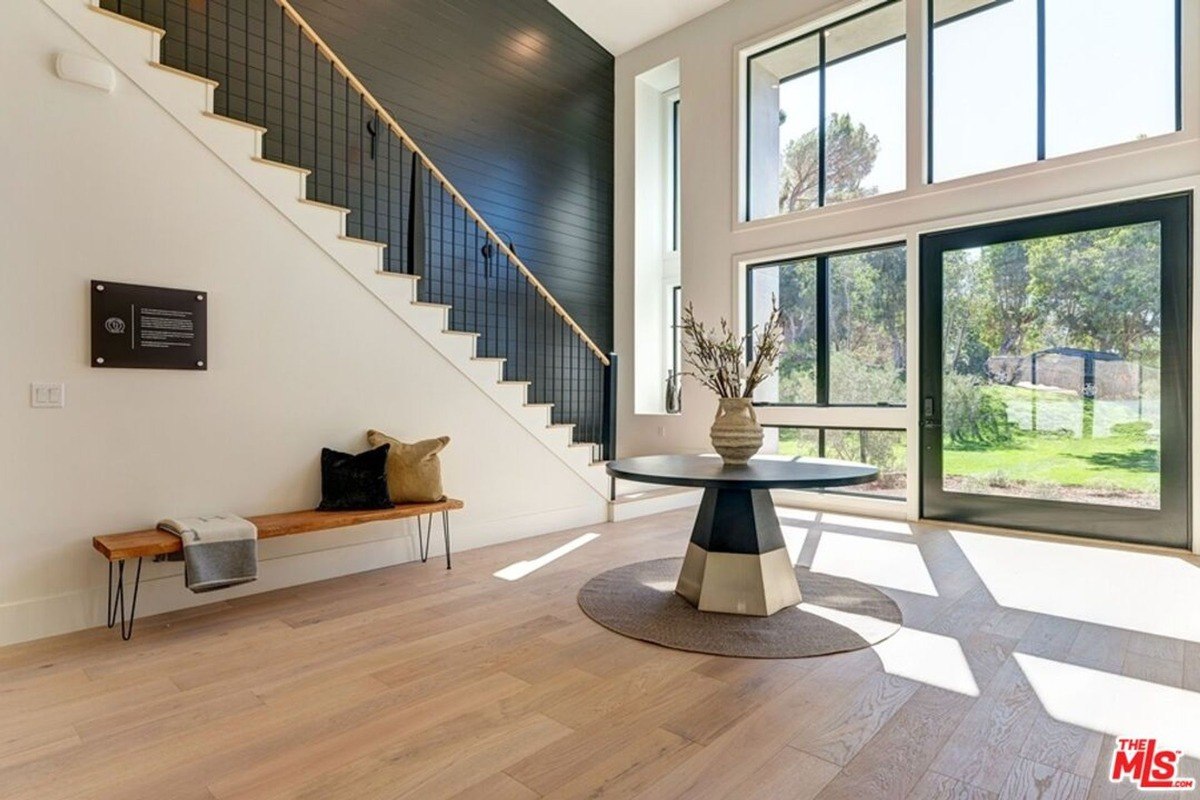 Entryway with expansive windows, a floating staircase, and a central round table.