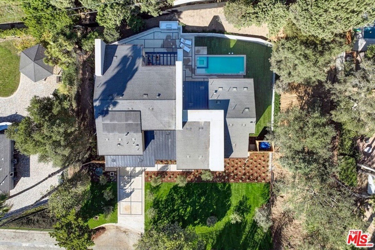 Aerial view highlights the home's architectural layout, backyard pool, and landscaped surroundings.