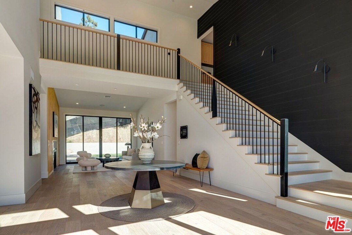 Open-concept living area featuring a two-story ceiling, natural light, and minimalistic decor.