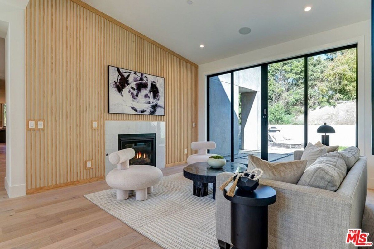 Fireplace wall with slatted wood paneling next to sliding glass doors leading to an outdoor space.