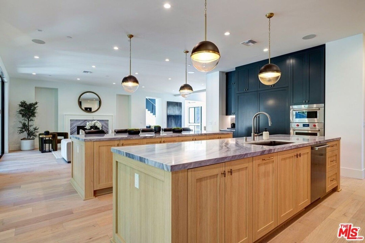 Spacious kitchen with a marble countertop island and dual pendant lighting extends into an open living space for a cohesive design.