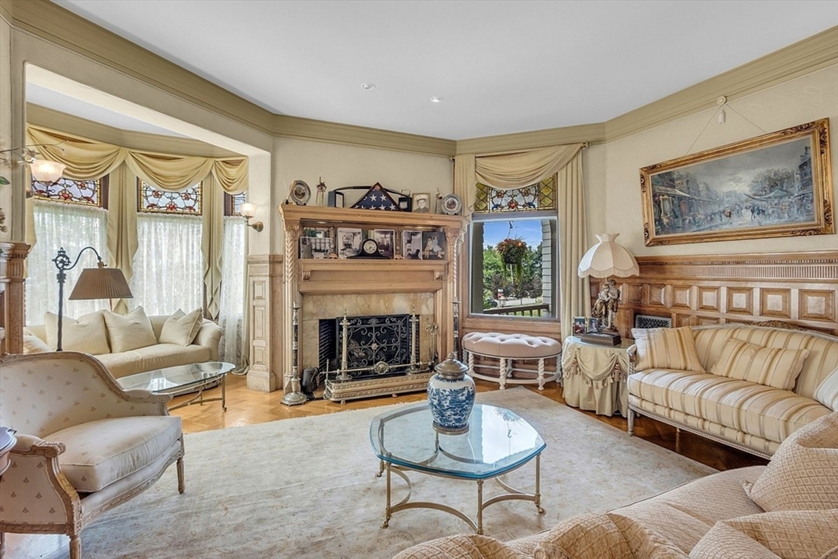 Another angle of the living room displaying antique furniture and a bay window.