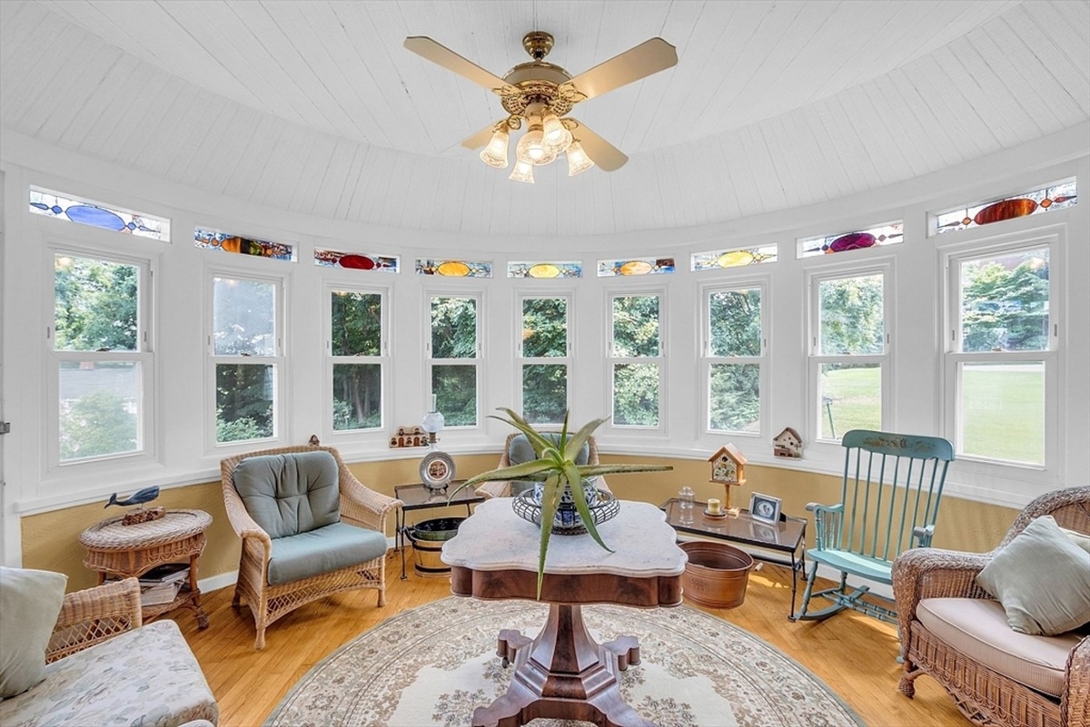 Formal dining room is highlighted by a large table, detailed wooden chairs, and a chandelier with stained glass windows in the background.