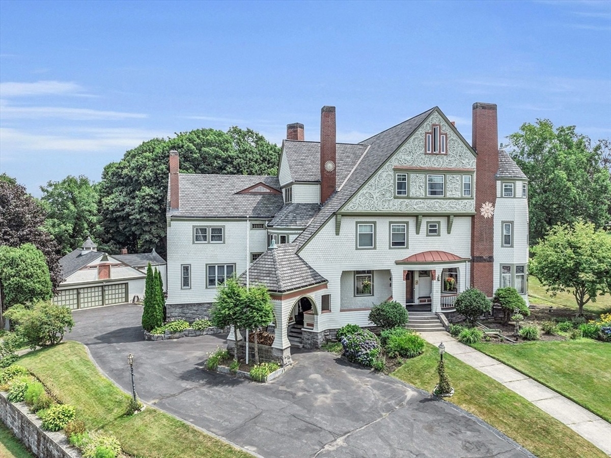 Expansive driveway leading to a Victorian-style residence surrounded by manicured greenery.