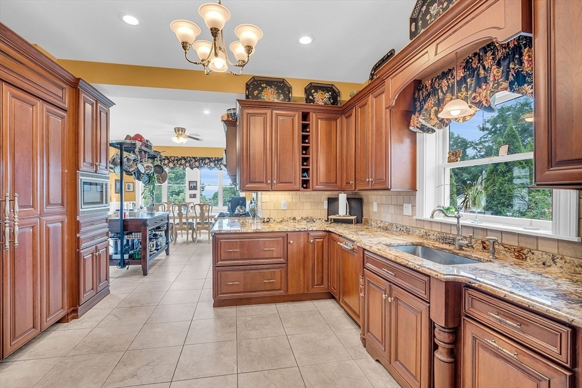 Breakfast nook includes a wooden table and chairs surrounded by panoramic windows with garden views and stained glass details above.