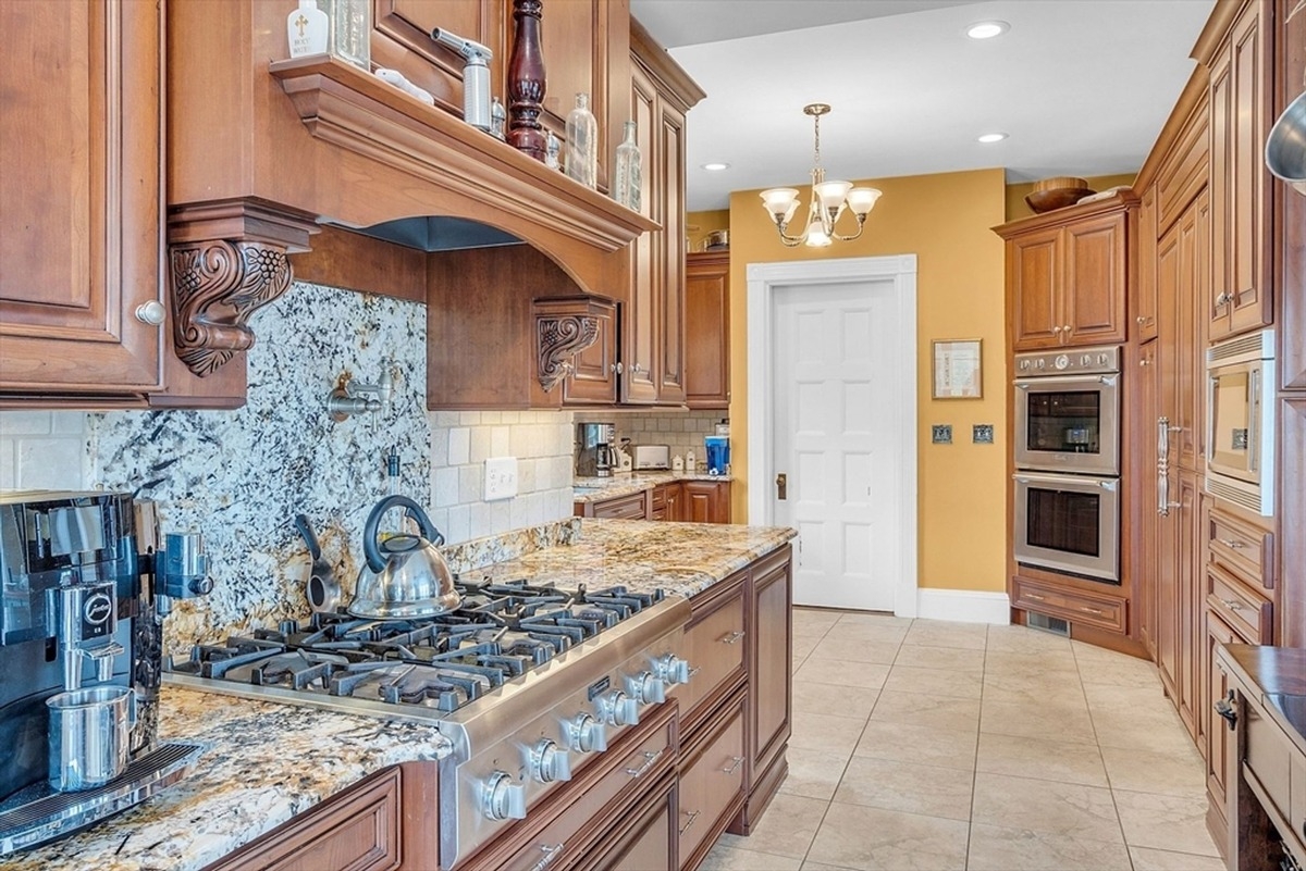 Kitchen features a granite backsplash, a six-burner stove, and cherry wood cabinetry.