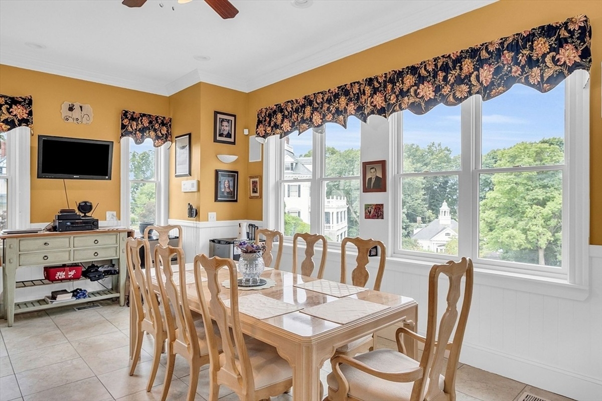 Dining area showcases a table with seating for six, bright yellow walls, and large windows.