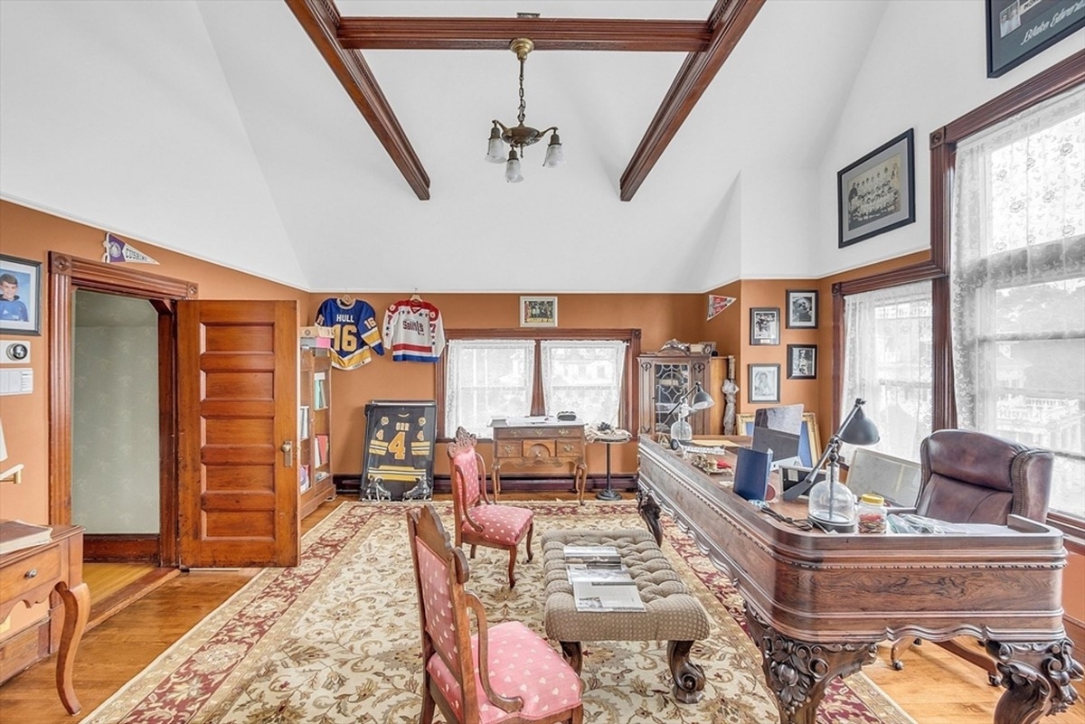 Ceiling beams accentuate the spacious home office, which features ornate furniture and collectibles.